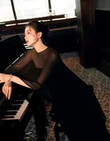 刘诗诗侧身立于三角钢琴旁，一袭黑色露肩礼服裙摆迤逦，指尖轻触琴键，眼神深邃望向远方