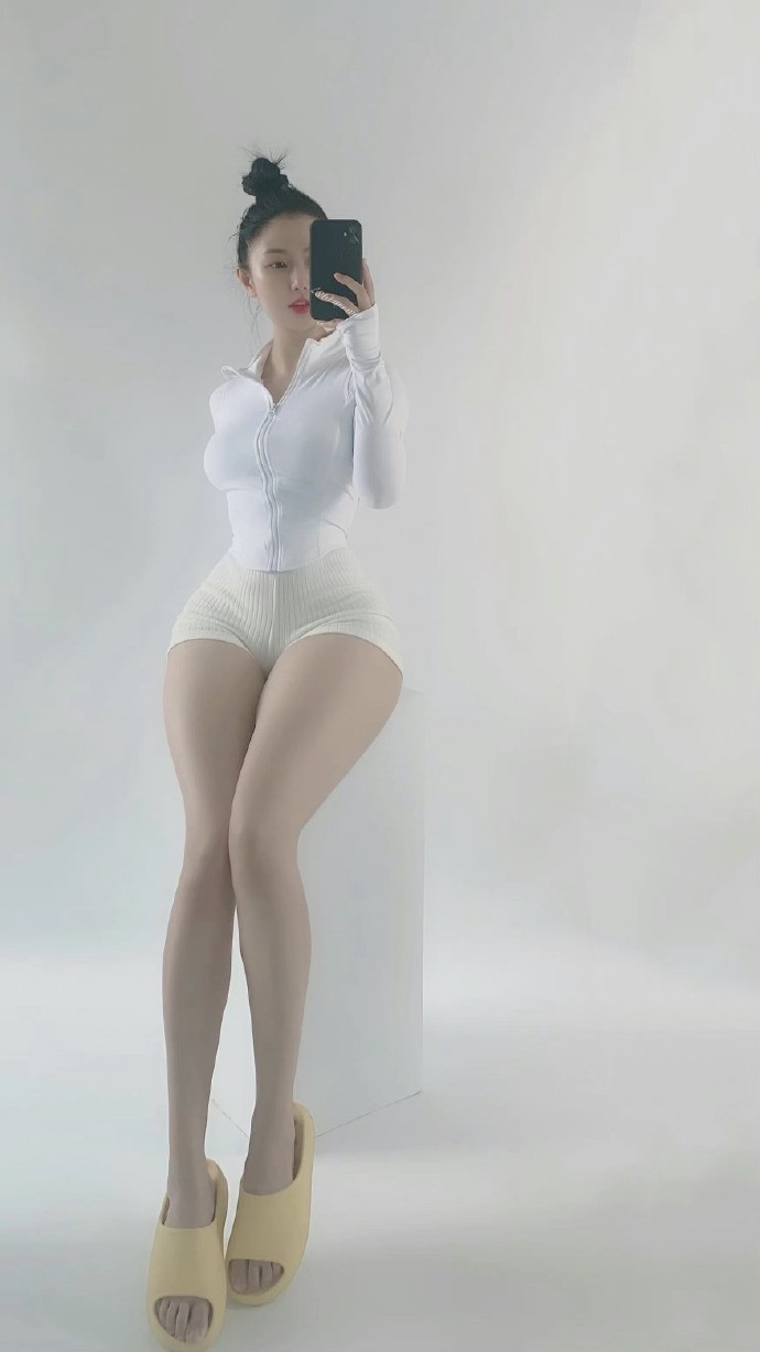 健身女性在灯光下展示其挺翘的臀部与结实的大腿后侧肌群，肌肤闪耀着健康的光泽