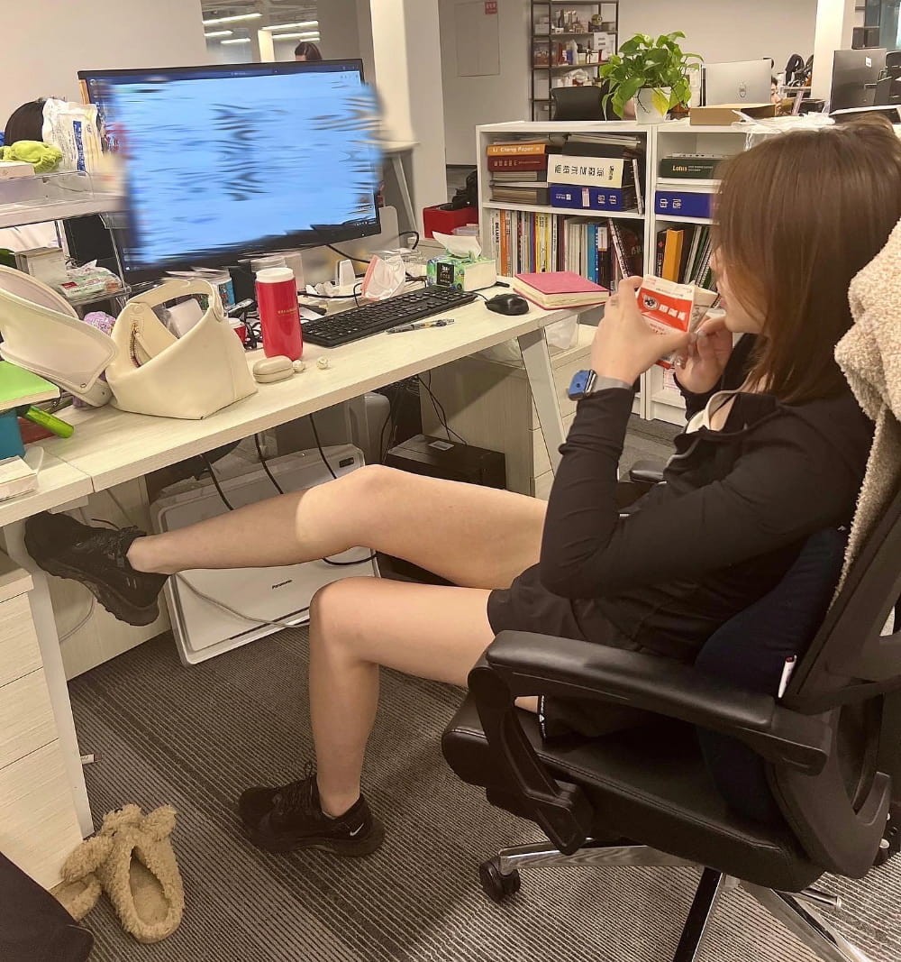 一位女职员的办公桌，桌上绿植茂盛，家人相框温馨，宛如一个微型家园