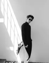 特写镜头下，王鹤棣立于窗格之前，光线照亮他半面脸庞与黑色衣衫的细腻纹理，眼神坚定有力