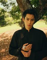 王鹤棣漫步于青石板路，身后是葱郁的竹林，一袭墨色身影在绿意中显得尤为醒目而飘逸