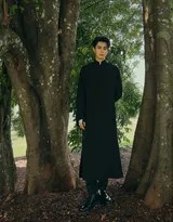 阳光穿过枝叶，在王鹤棣与青灰墙面上描绘出灵动的光斑，他神情淡然，似在聆听自然低语