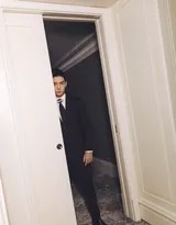 盛一伦单手轻插裤袋倚靠墙边，肩线平直挺拔尽显从容不迫的男性魅力