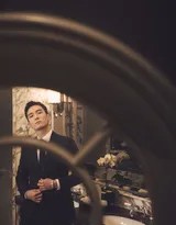 盛一伦侧身立于光影交界处，西装轮廓如雕塑般精致，眼神深邃凝视远方