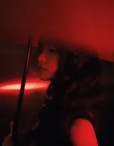 田曦薇于潮湿街巷中侧身回眸，手持猩红长伞，黑色抹胸裙与暗夜融为一体，眼神疏离而神秘