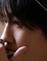 朱一龙坐在巴黎街头长椅上，双手轻握，粉色西装与深色背景对比鲜明，神情专注而温润