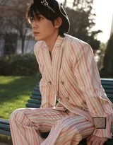 朱一龙侧身立于巴黎古典建筑前，粉色条纹西装与斑驳墙面形成温柔对比，眼神沉静望向远方