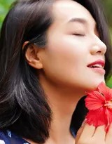 朱丹坐于公园长椅，手轻抚裙摆，低头含笑，静谧午后散发出温柔娴雅的迷人魅力