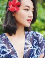 朱丹身着蓝底白色碎花连衣裙，于公园绿荫下侧身回眸浅笑，阳光透过树叶洒落肩头