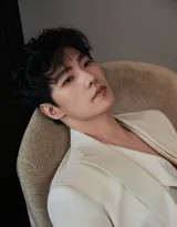 杨洋立于窗前沐浴阳光，侧颜俊美轮廓清晰，白色西装更添温柔暖男气质