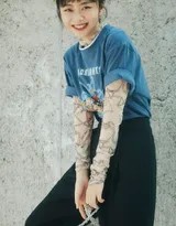 谭松韵倚靠在都市街角的墙壁，身着休闲运动装，丸子头利落，在午后光影中展露宁静而放松的恬淡微笑，仿佛时光悄然静止。