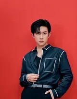 易烊千玺回眸瞬间，红色背景如剧场帷幕，蓝色衣衫随动作泛起轻柔褶皱