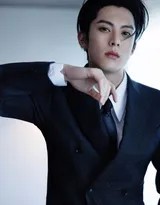 王鹤棣微微低头嘴角含笑，灯光洒于侧脸，为硬朗西装造型增添一抹温柔