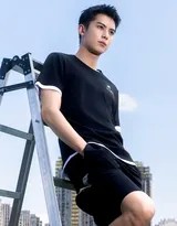 王鹤棣倚靠栏杆，身穿深色运动背心与短裤，眼神坚定，展现运动后的率性与活力。