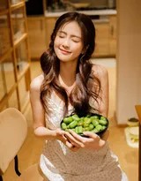 白鹿身穿浅绿色绣花吊带裙，手持一束白花对镜头甜美微笑