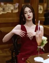 饮尽果汁后她放松地向后靠去，红裙在椅面铺开如花瓣，满足的笑意从眼角蔓延至整个脸庞