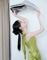 祝绪丹身着橄榄绿吊带长裙静坐，阳光洒落肩头，静谧时光中绽放从容浅笑