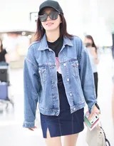 秦岚低头含笑行走，牛仔外套与棒球帽的搭配简约时尚，整体造型充满青春活力。