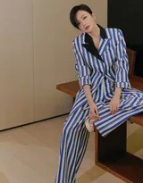 秦岚低头浅笑瞬间，短发自然垂落，蓝白条纹西装敞开，内搭简约白色打底，氛围轻松惬意，捕捉到冷峻造型下一抹温柔