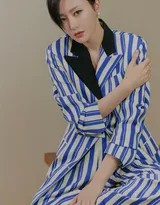 秦岚侧身凝视镜头，蓝白细条纹西装外套剪裁精良，短发微遮脸颊，眼神自信而深邃，背景光影交错营造出高级质感