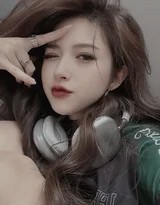 少女侧坐床边，斑驳光影洒在黑色吊带裙上，眼神沉浸在耳机传来的私人旋律中