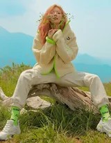 泫雅坐在草地上雙臂輕抱膝蓋展現寧靜沉思的瞬間