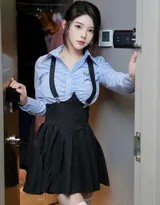 爱酱跪坐于柔和光影中，黑色背带裙勾勒出身体曲线，她轻咬手指，眼神迷离地望向镜头，充满故事感