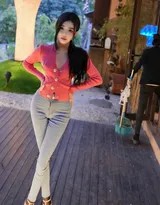 龙雪儿倚靠街角，红衣与砖墙形成色彩碰撞，牛仔裤裤脚微卷露出脚踝，高跟鞋尖点缀精致女人味