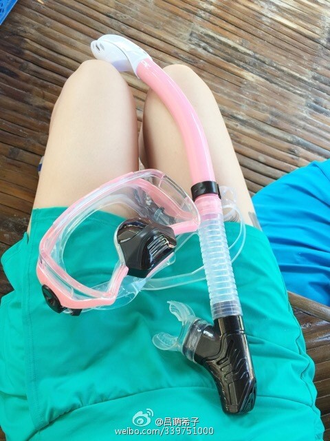 吕帅希倚靠窗前，一袭短裙映衬出她修长而白皙的腿部，阳光洒落更添温柔气息