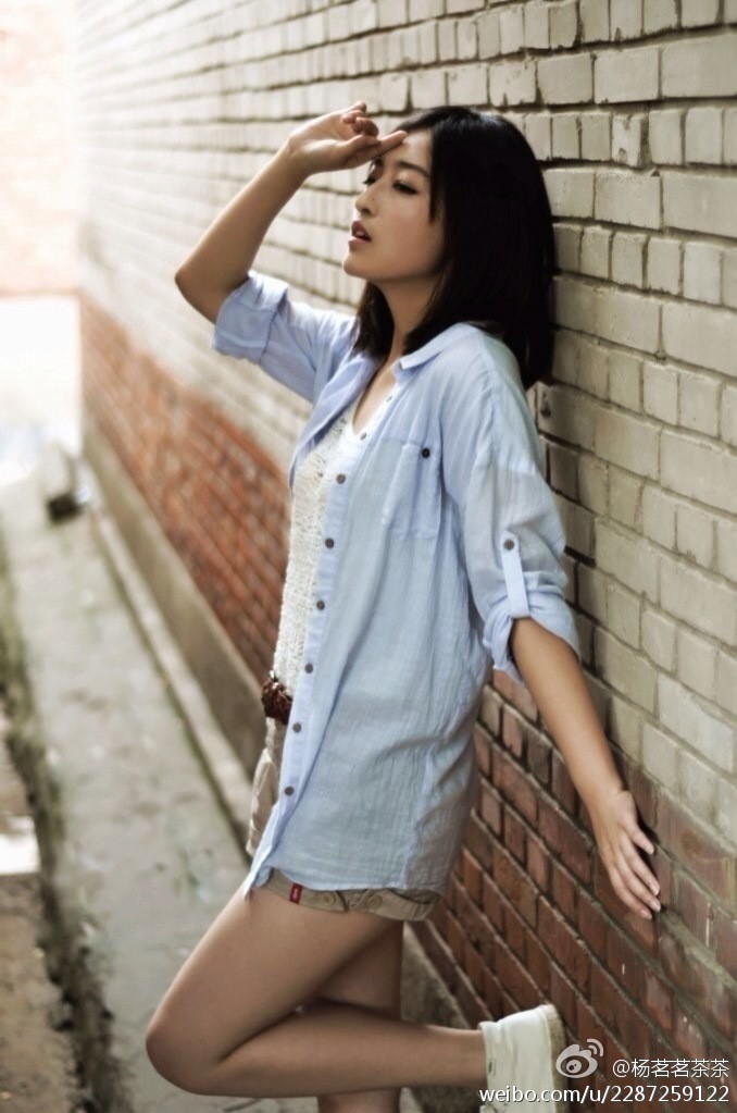 杨茗茗休闲装扮，单手撑地，回眸一笑，自然长发披肩，整个画面充满动感与生活化的美好。