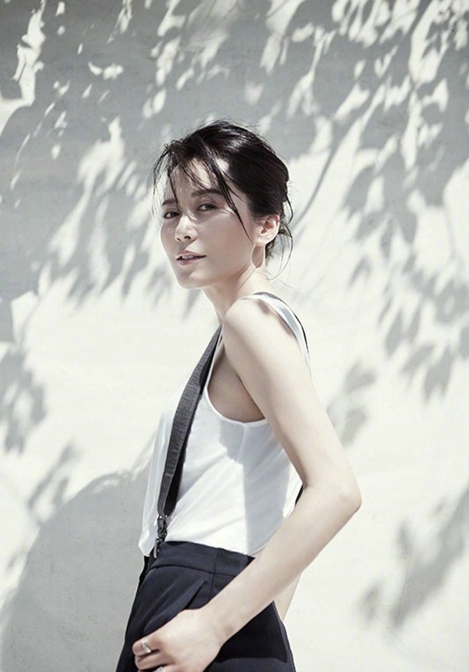 俞飞鸿侧身凝望窗外，米色针织衫衬出温柔侧影，眼神深邃而宁静