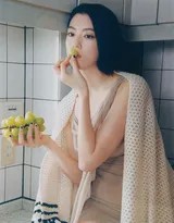 三吉彩花身着简约上衣倚靠窗边，午后阳光为她的侧脸镀上柔和金边，眼神疏离而深邃