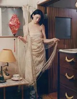 写真拍摄花絮般的瞬间，她对着镜头整理头发，表情自然生动，捕捉了工作状态外的灵动一瞥