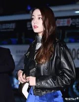 迪丽热巴身着皮衣倚靠墙边，姿态放松却气场全开，眼神中流露出不经意的洒脱与酷感