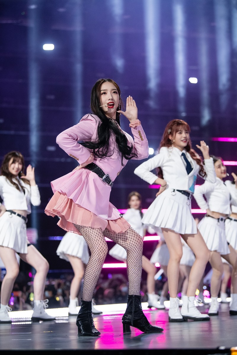 孟美岐在舞台中央纵情起舞，丝袜映衬出腿部优美曲线，灯光下身影摇曳生姿