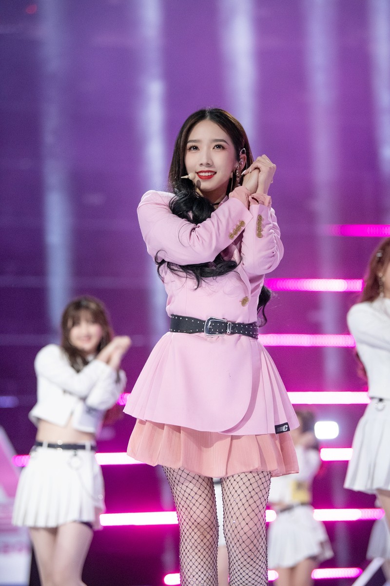 孟美岐旋转舞姿，丝袜随风轻扬，腿部动作优雅连贯，舞台背景绚丽多彩