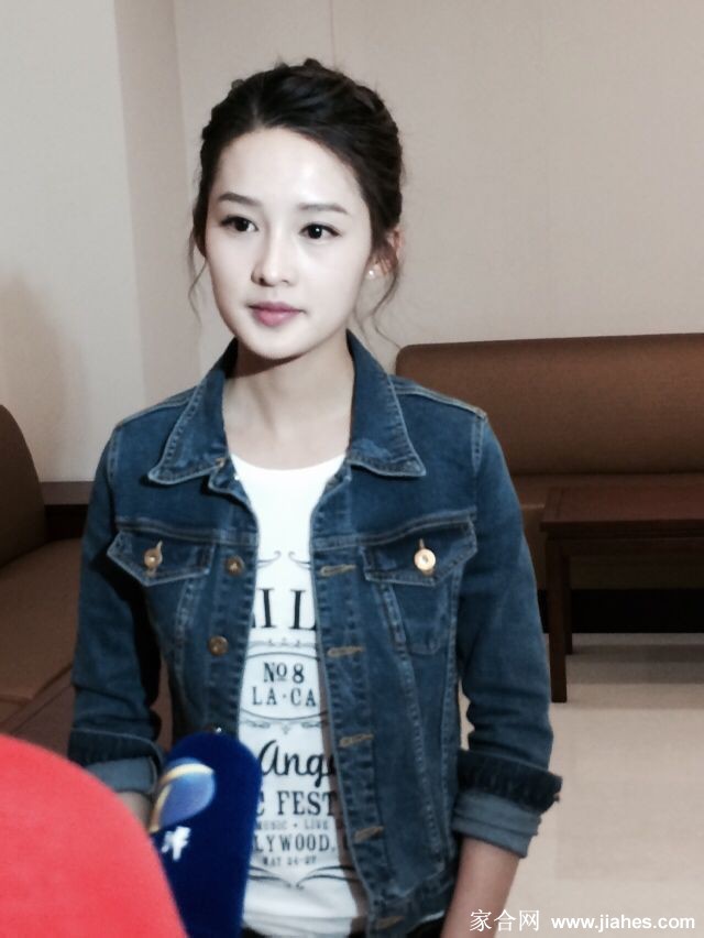 李沁低头细心地为一个穿红裙的小女孩整理头发和衣领，动作轻柔，充满母性的关怀，小女孩乖巧地站着。