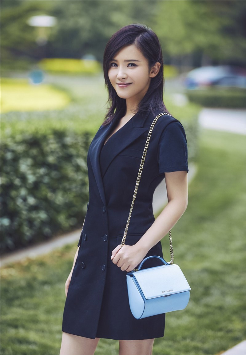 杨子姗手提黑色皮质单肩包行走街头，整体造型简洁利落，散发着都市女性的独立气质