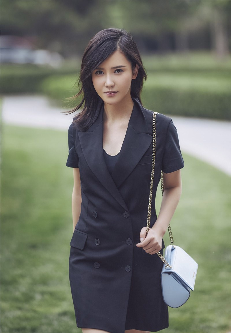 杨子姗身穿拼色皮夹克与皮裤，肩挎黑色皮质单肩包站立街头，眼神坚定而自信