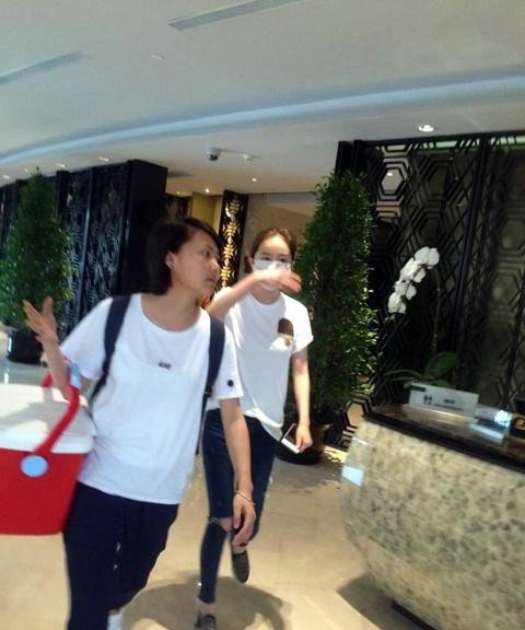 见镜头后急忙侧身捂脸，指缝间眼神略显无奈