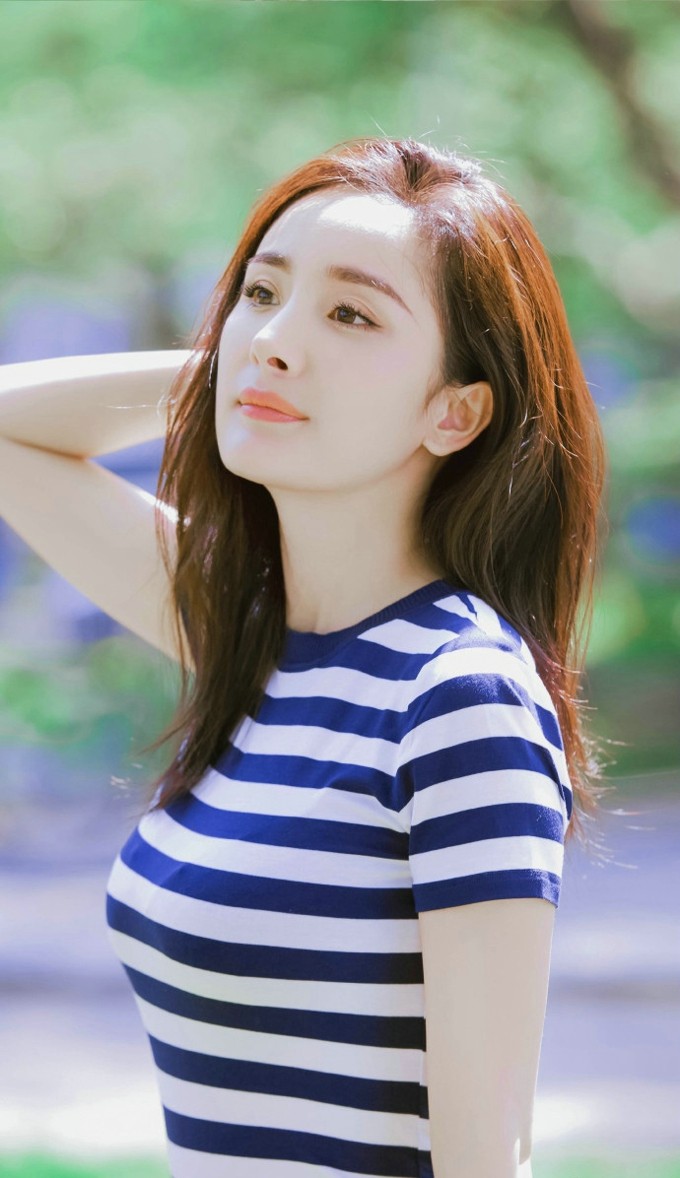 杨幂与各种彩色卡通玩偶依偎在一起，笑容治愈温暖，画面充满童真