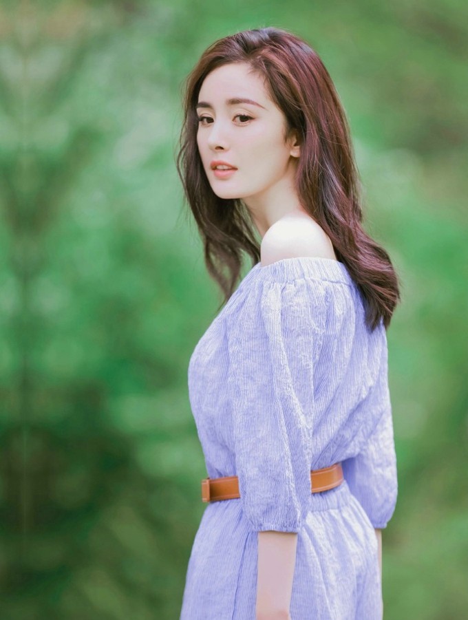 杨幂对镜浅笑，眼神温柔而专注，柔和光线勾勒出她精致的面部轮廓