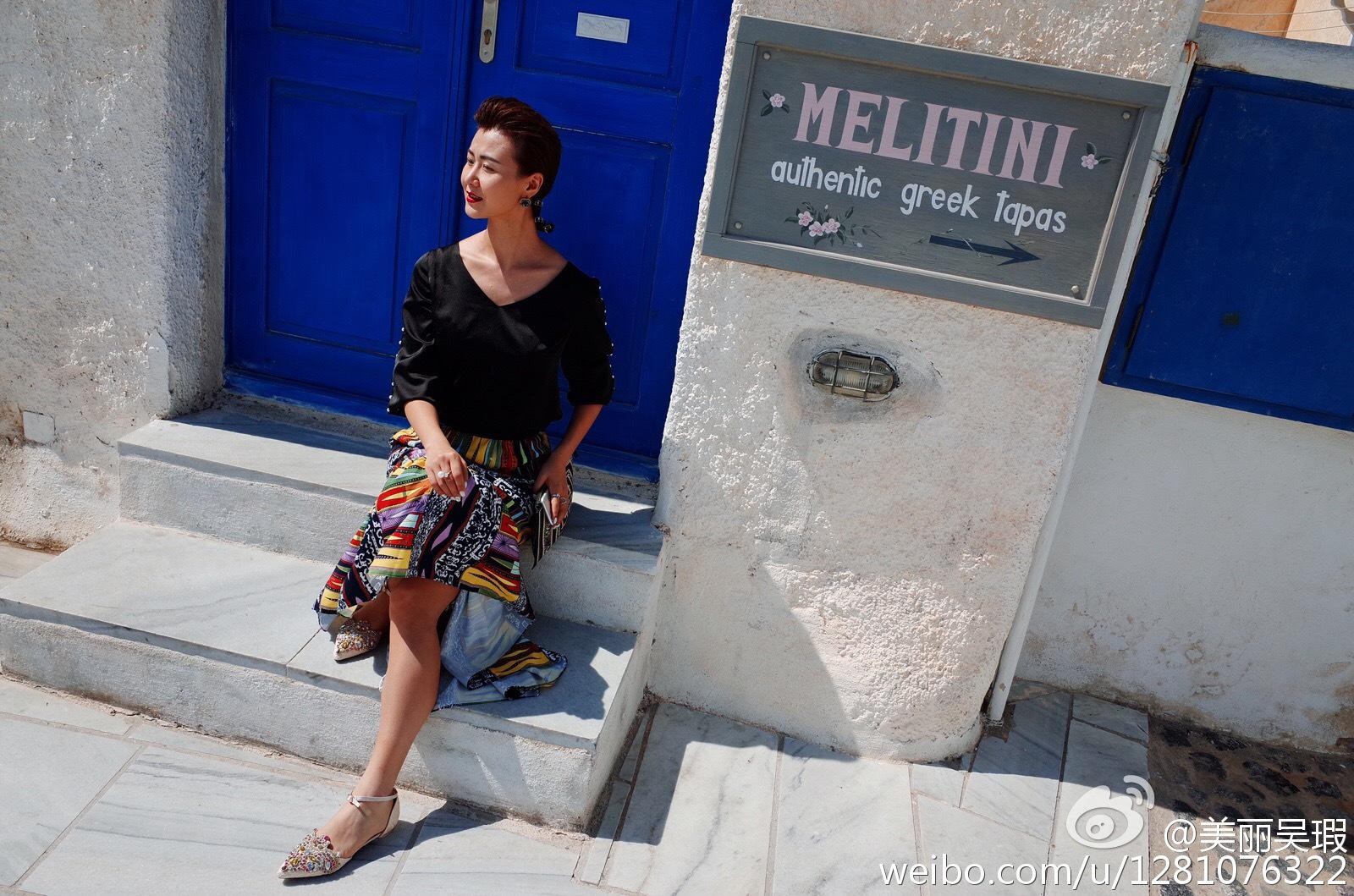 吴瑕漫步街头，身着深色外套搭配短裙与高跟鞋，回眸间尽显知性优雅