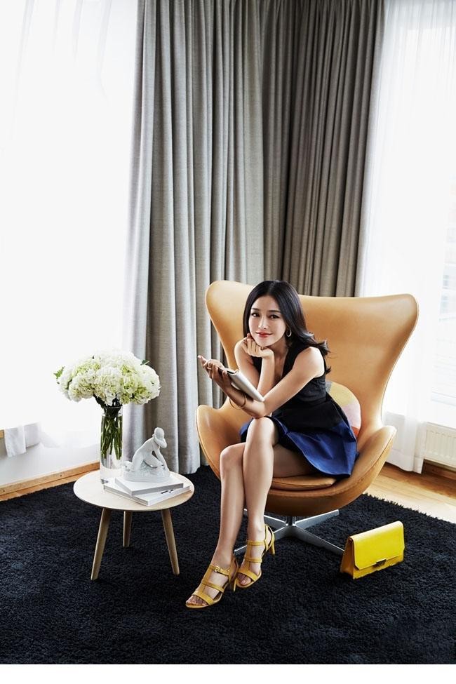 秦岚置身花丛中俏皮捧脸，眼中闪烁着灵动光芒如少女般娇俏