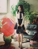 优雅侧坐的美女，修长美腿自然伸展，白衫黑裙映衬静谧氛围