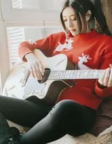 侧身坐在椅子上的莫小琪，手指轻抚吉他琴弦，眼神温柔地望向窗外