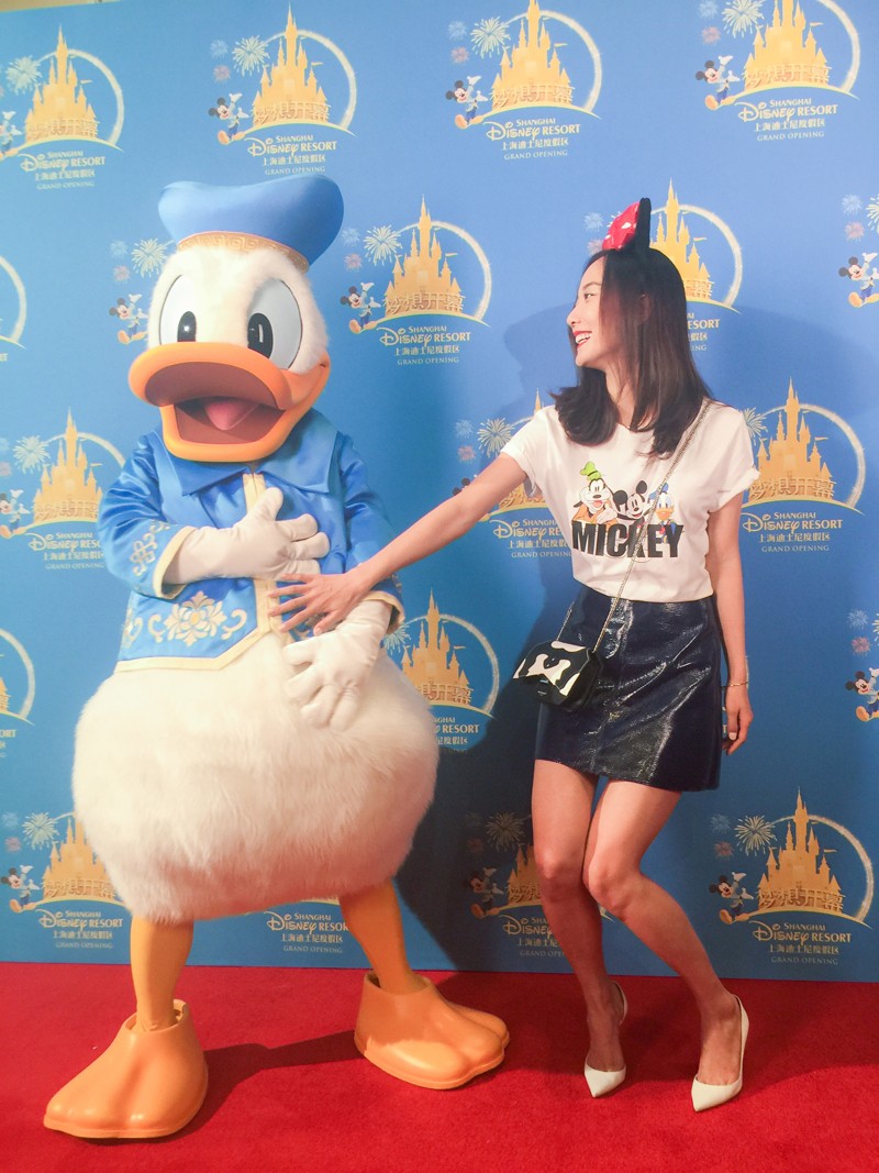 王珞丹俏皮地弯曲手臂，与身旁身穿水手服的唐老鸭搞笑比拼肌肉力量