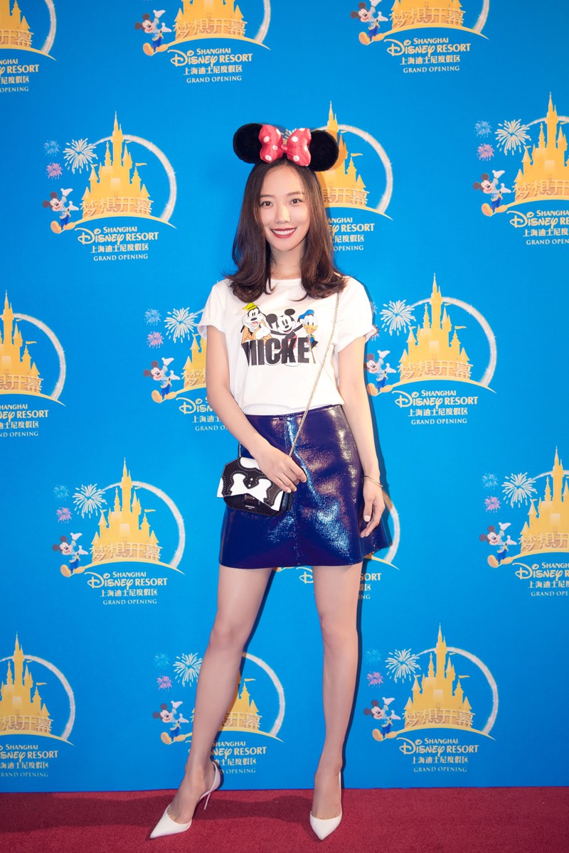 王珞丹头戴米奇耳朵发卡，身着简约白T恤与蓝裙，在红毯上展露明亮笑容