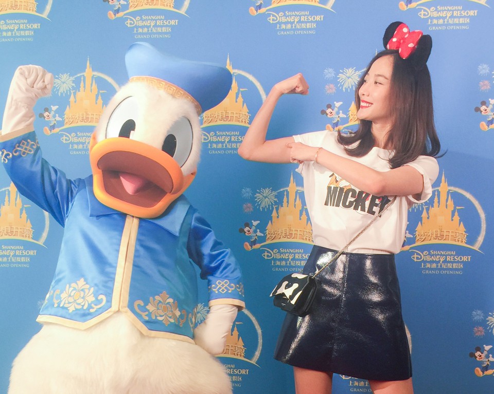 王珞丹微微俯身，面带温柔笑意，亲密地用手臂环抱可爱的唐老鸭