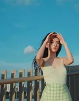 阳光下少女闭上双眼感受微风，吊带裙衫勾勒出优雅肩线，静谧时刻美好如画